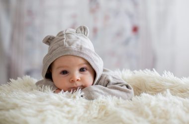 Sweet baby boy in bear overall, sleeping in bed with teddy bear