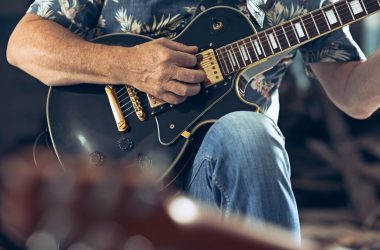 Repetition of rock music band. Electric guitar player and drummer behind the drum set.